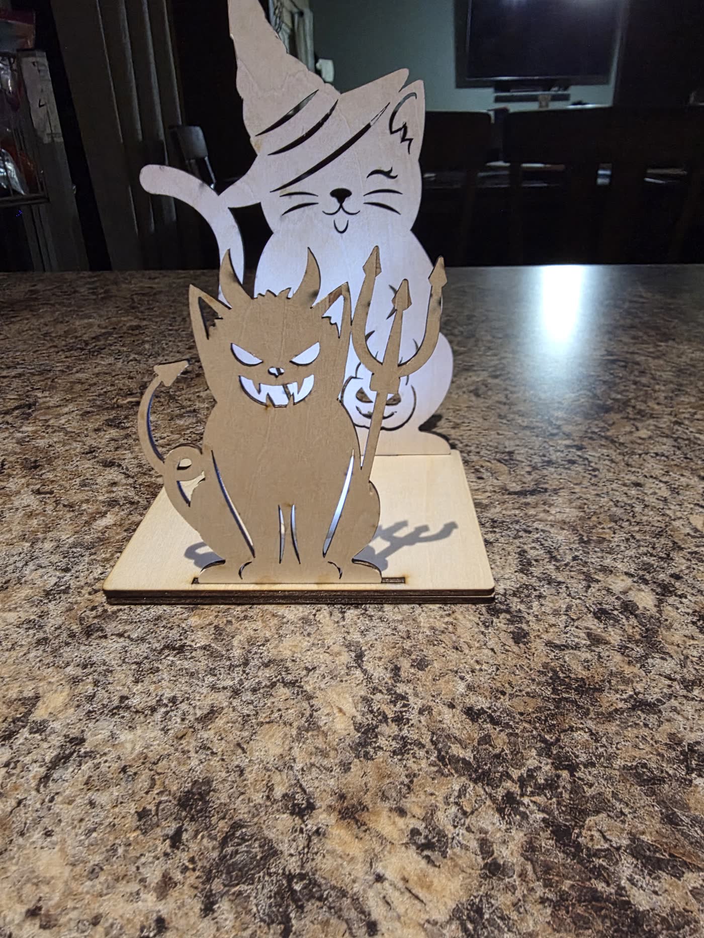 Wooden Halloween lantern of a witch cat behind a grinning devil cat holding a trident.
