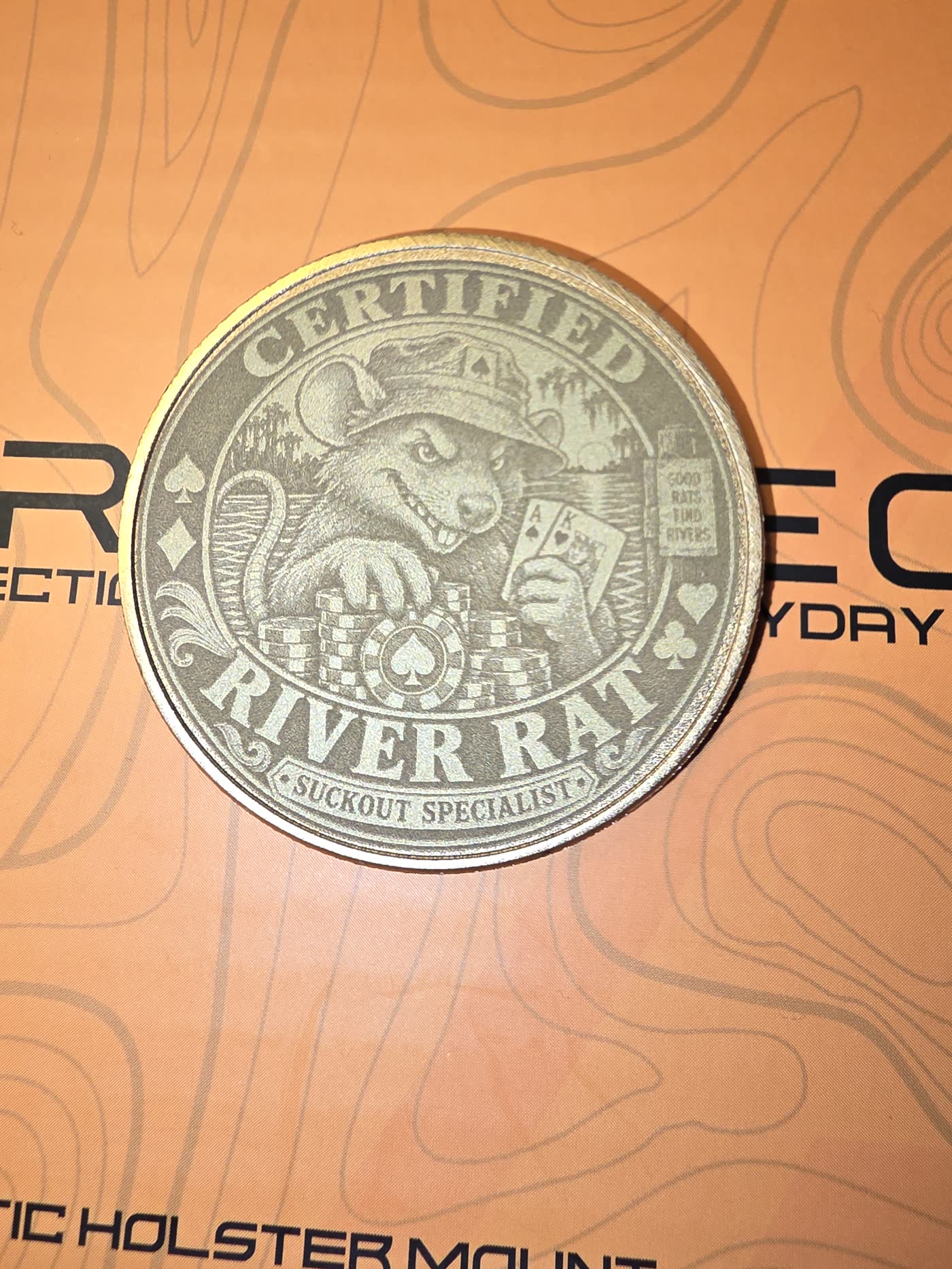 Oberedge River Rat metal card guard on an orange topographic mat.